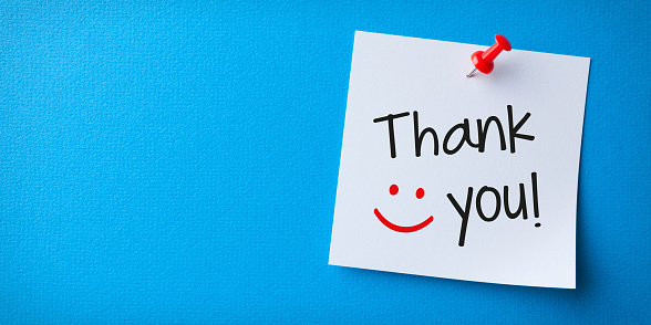 White Sticky Note With Thank You And Red Push Pin On Blue Cardboard