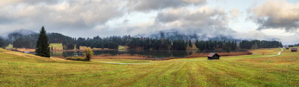 Alpine lake Geroldee or Wagenbruchsee, Bavaria, Germany. Autumn overcast, foggy and drizzle day. Picturesque traveling, seasonal, weather, and rural nature beauty concept scene.