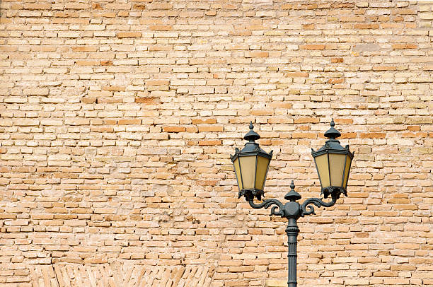 Varberg, Sweden - April 01 2023: Street lamp by a tall stone wall.