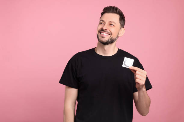 istock Happy man holding condom on pink background. Space for text 1494097450