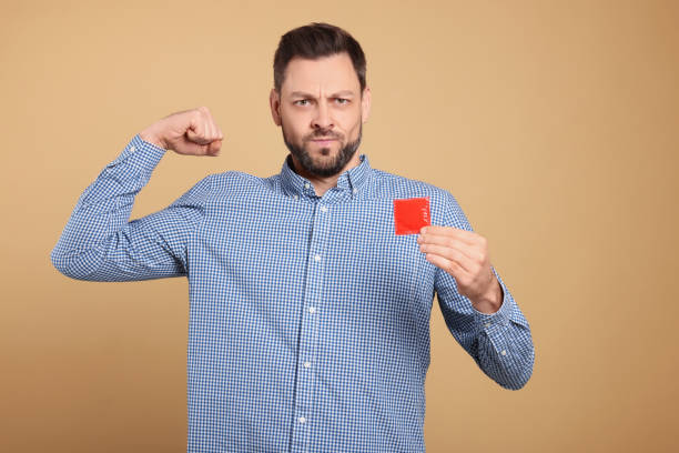 istock Handsome man holding condom on beige background 1494097459