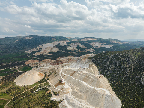 Landscape view of an open cast marble quarry in Carrara, Tuscany, Italy showing the heavy duty equipment and rock face