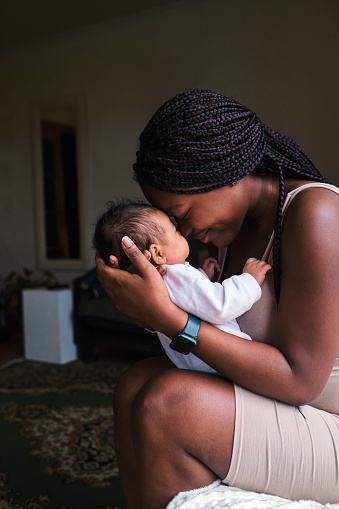 Vertical profile photo of a tender scene of an african mother and a newborn at home