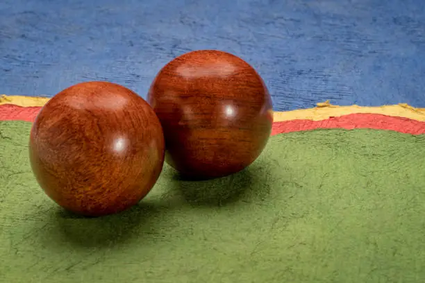 a pair of wooden Chinese medicine balls against colorful abstract paper landscape