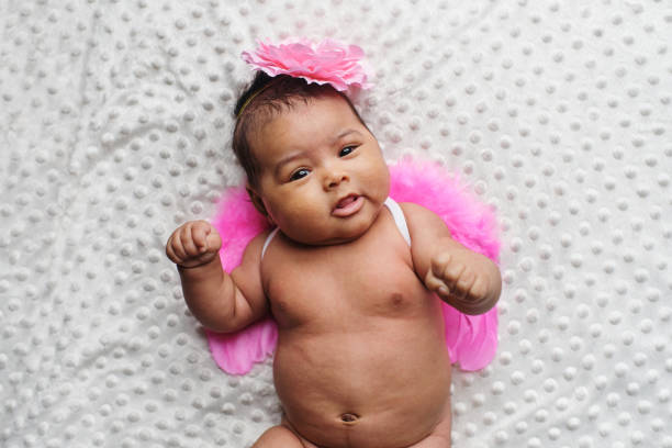 Top view portrait of an african newborn dressed with angle pink wings and a flower