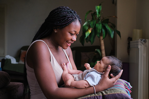 Profile portrait of a happy african mother with her baby on arms at home