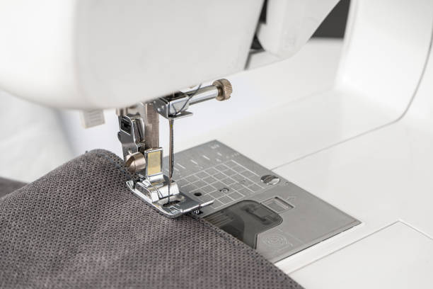 istock Modern sewing machine presser foot with gray fabric and thread, closeup 1494099814
