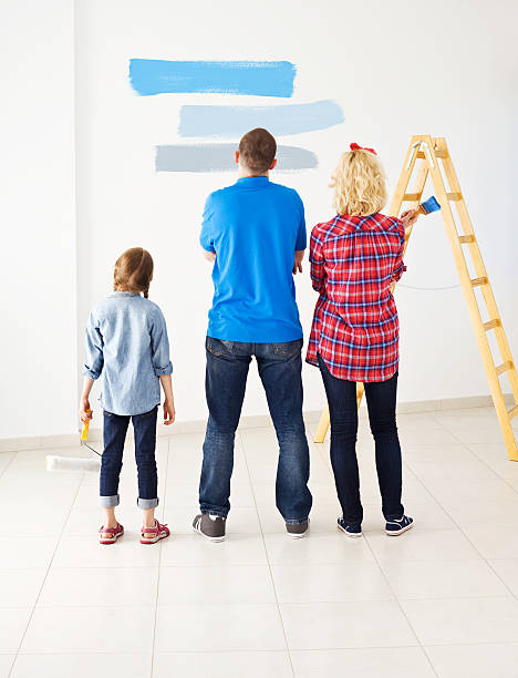Which color is the best? Young parents with little daughter looking at the wall with color samples and choosing the best color. Back view. house painter ladder paint men stock pictures, royalty-free photos & images