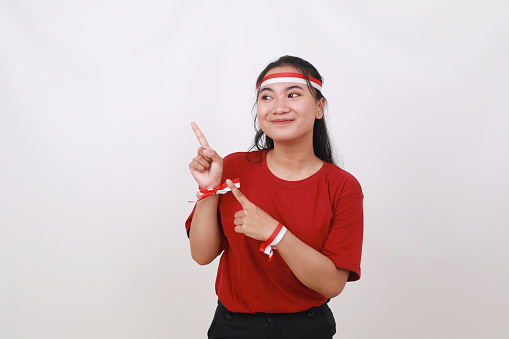 Young Indonesian girl celebrate indonesia independence day while pointing something on blank space