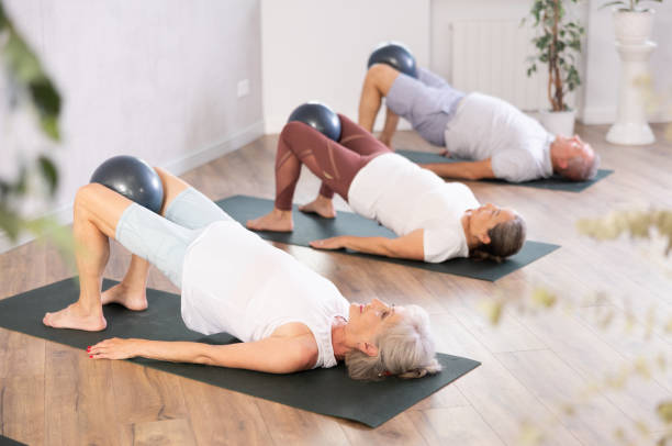 istock Active woman doing exercises with pilates ball during group training at gym indoor 1494113095
