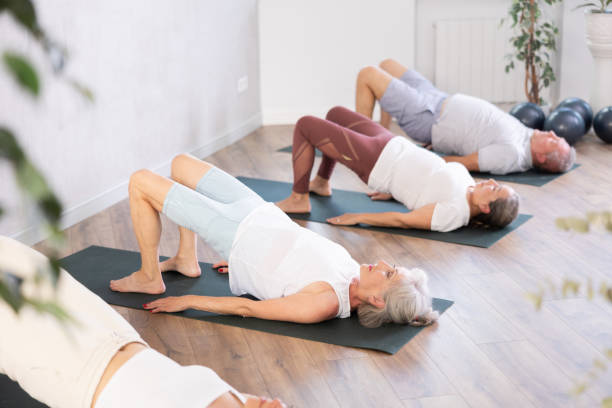 istock Group of active women doing different yoga exercises lying on their back 1494113145