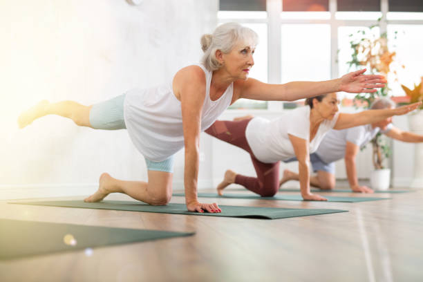 Mature women pushing-up and being on hands and feet with straight body while practicing Plank Pose or Makara Adho Mukha in fitness center