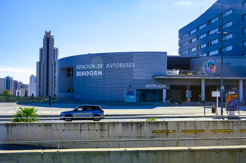 Benidorm, Spain - April 21, 2023: A car on a bridge highway in the foreground, with a building in the background prominently displaying the text \