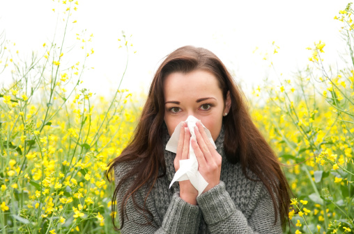 beautiful young woman in rape field has hay fever