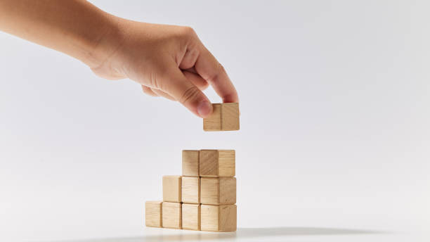 istock Hand putting wood cube arranged stacked as stair step shapes, a business concept 1494124667