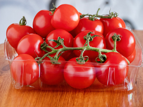 Freshly harvested ripe vine-ripened red tomatoes in a plastic shell