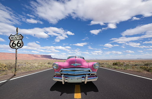 Vintage pink classic car oldtimer driving through National Park USA on Route 66