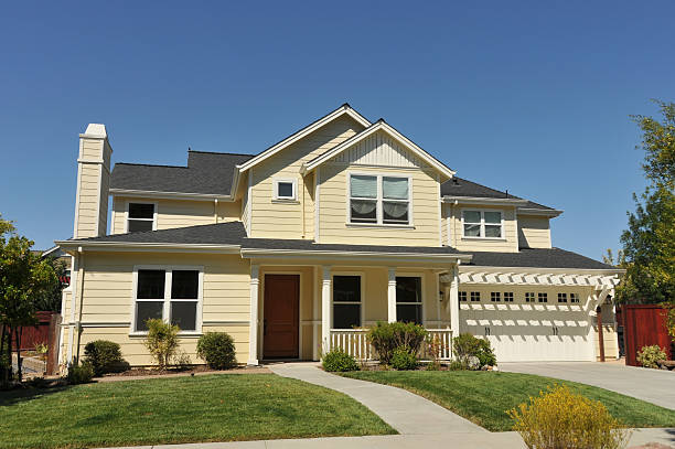 Yellow two story house with garage and driveway and fence stock photo