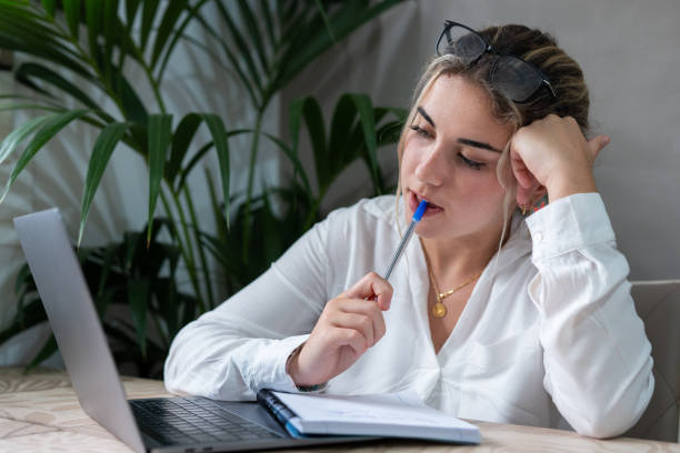 Portrait of serious millennial caucasian female student sit at desk at home study online on laptop. Thoughtful young attractive woman use computer take distant course or training. Education concept. retrato de una estudiante caucásica milenaria seria sentada en el escritorio en casa estudia en línea en una computadora portátil. la joven reflexiva y atractiva usa la computadora para tomar un curso o entrenamiento a distancia. concepto de educación.