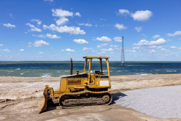 River shore construction: yellow grader and communication tower. Communication tower in the river on sky background in Downtown of Newport News, VA