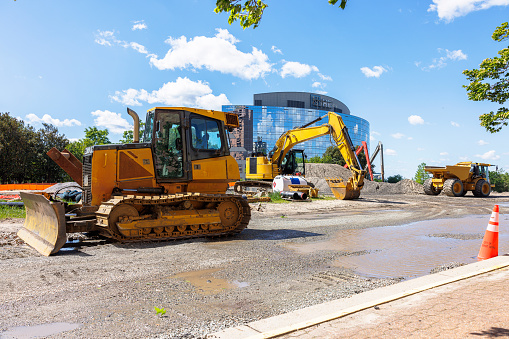 Caterpillar bulldozer and construction machinery in financial district. Building road with excavator and grader in Downtown of Newport News, VA