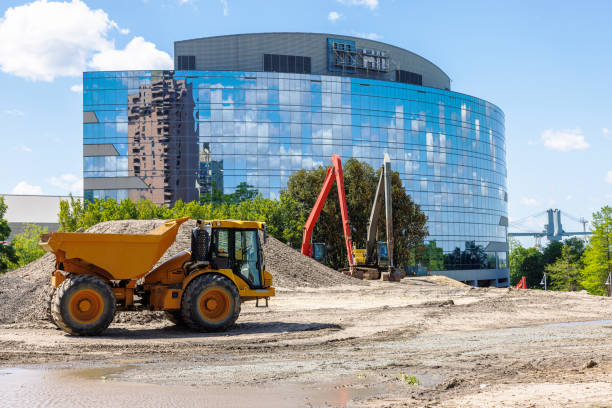 istock Financial district construction site in Downtown. Facade glazed office building with reflection. Dump truck and backhoe on sandy construction site against blue sky in Newport News, VA 1494136458