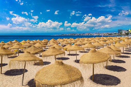 Umbrellas on public beach in Estoril in a beautiful summer day, Portugal