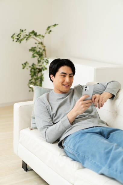 istock Japanese man watching his phone at home 1494140068