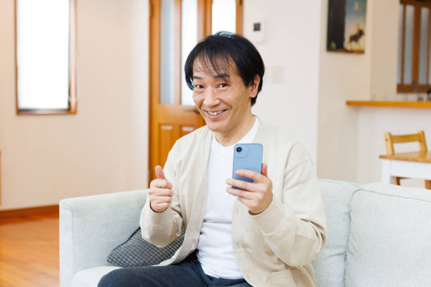 istock Mature Japanese man using a mobile phone at home 1494145506