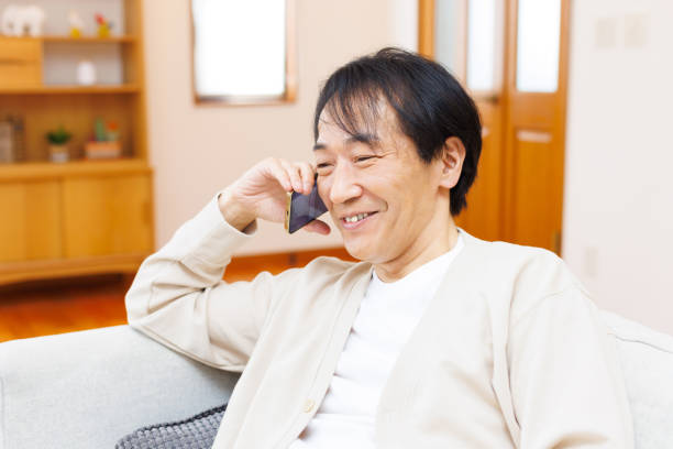 istock Mature Japanese man talking on phone at home 1494145514
