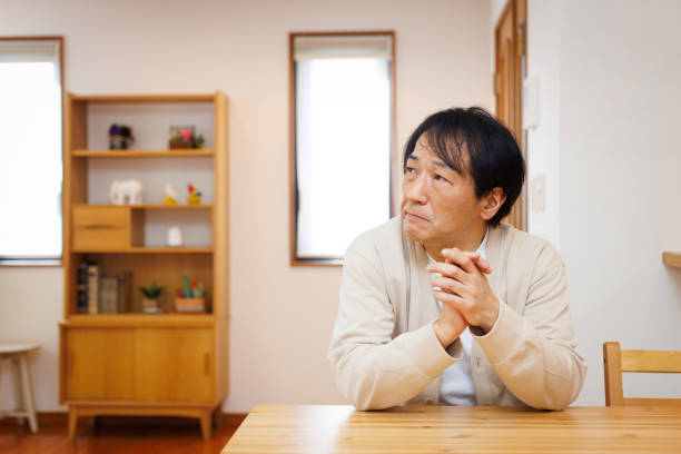 istock Mature Japanese man sitting at dining table and contemplating 1494145526
