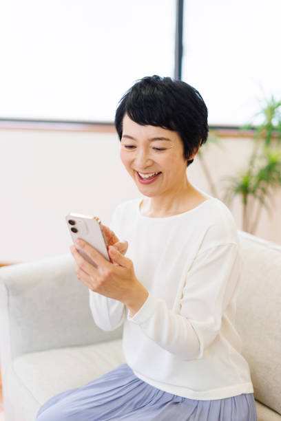 istock Mature Japanese woman using mobile phone at home 1494146346