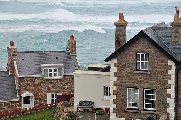 Telephoto image coastal built homes with rolling waves in the background.