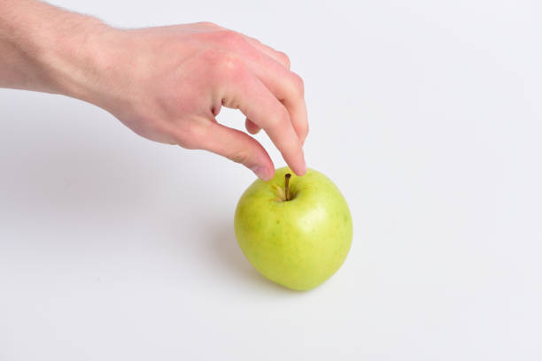istock Male hand reaches light green apple. Apple fruit on white 1494159589