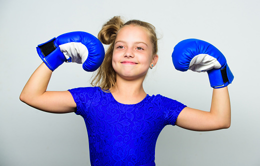 Girl child happy winner with boxing gloves posing on grey background. She feels as winner. Upbringing for leadership and winner. Feminist movement. Strong child proud winner boxing competition.