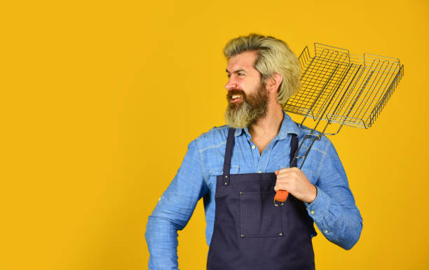 istock Tools for roasting meat outdoors. Picnic and barbecue. ready for barbecue party. Culinary concept. summer weekend. happy hipster hold cooking utensils for barbecue. bearded man chef. copy space 1494160367