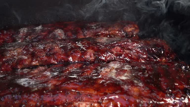 Three racks of succulent ribs, seasoned to perfection, sizzle and simmer on the barbecue, smoke swirling around them, infusing them with a tantalizing aroma.