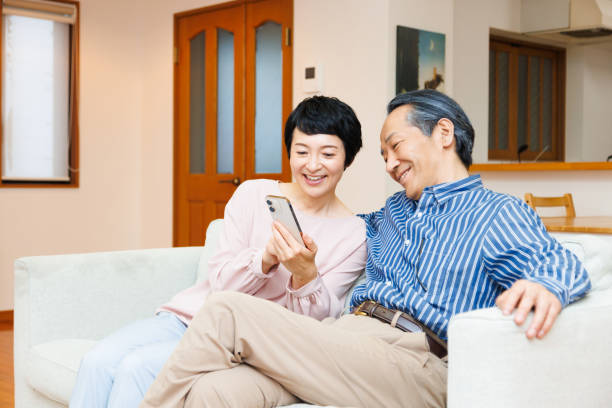 夫に携帯電話を見せる熟女の日本人女性 - senior couple ス��トックフォトと画像