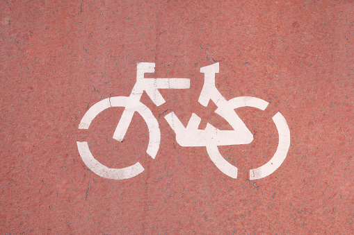 Symbol of a bicycle on red asphalt, painted white.