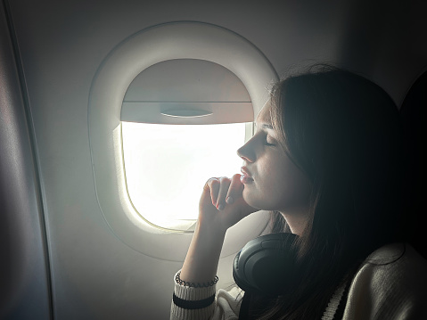 Young Girl With Headphones Chilling Near Window On The Plane