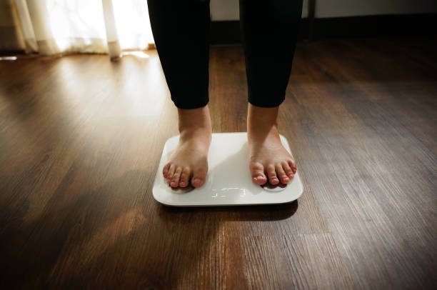 istock Fat diet and scale feet standing on electronic scales for weight control. 1494179156