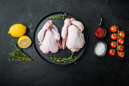 Fresh raw chicken meat with herbs spices, on black background, top view with copy space for text