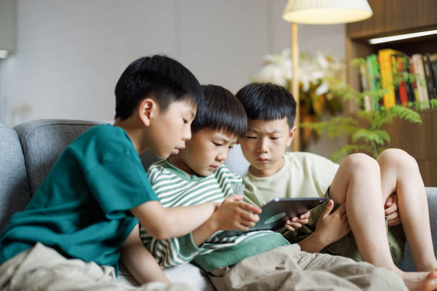 istock Three  boys playing games on a digital tablet on the sofa 1494179622