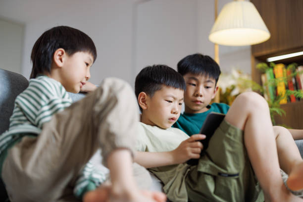 istock three Asian boys watching videos at home using digital tablets 1494179646