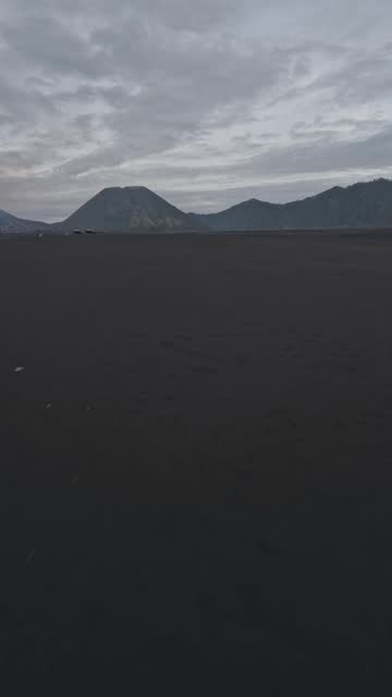 Vertical video. Black sand dirt volcano lava field desert surrounded gloomy 4k
