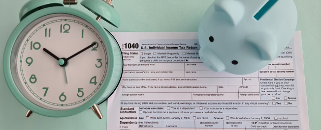US Tax Form 1040 alarm clock and piggy bank. Time to pay taxes