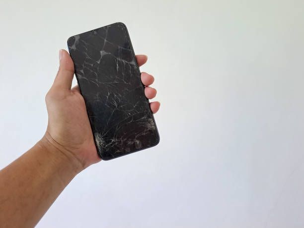 istock Man's hand holding black smartphone with a broken screen isolated on white background 1494188218