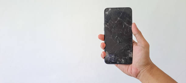 istock Man's hand holding black smartphone with a broken screen isolated on white background 1494188324