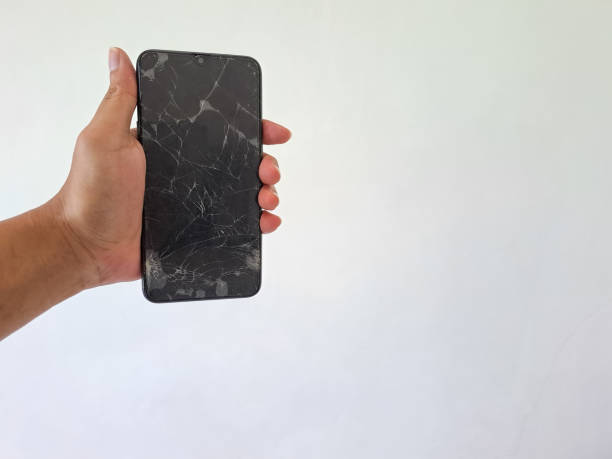 istock Man's hand holding black smartphone with a broken screen isolated on white background 1494188391