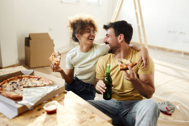istock Young cheerful couple talking while eating pizza on a break from home renovation process. 1494189395